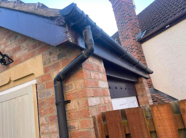 Old wooden fascia with cracked soffit and leaking guttering before replacement