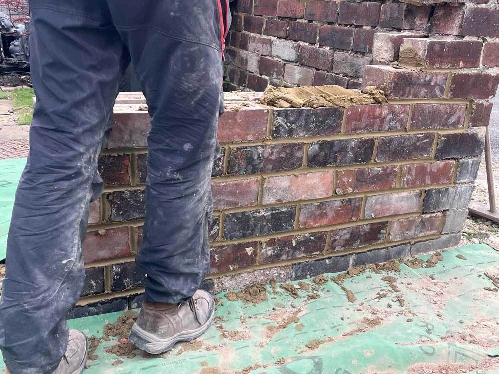Worker’s legs in front of freshly pointed low brick wall