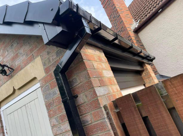 New UPVC guttering and fascia installed, showing clean roofline, black soffits, and completed replacement work