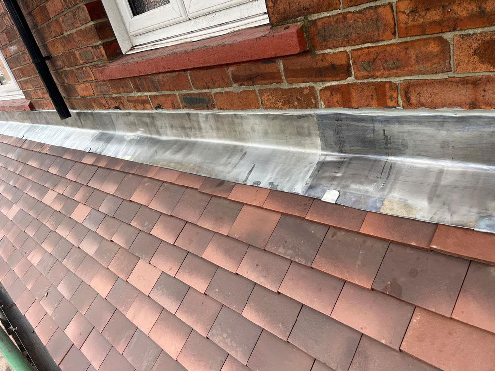 New lead flashing installed where a pitched roof meets a brick wall on a home in Newcastle.