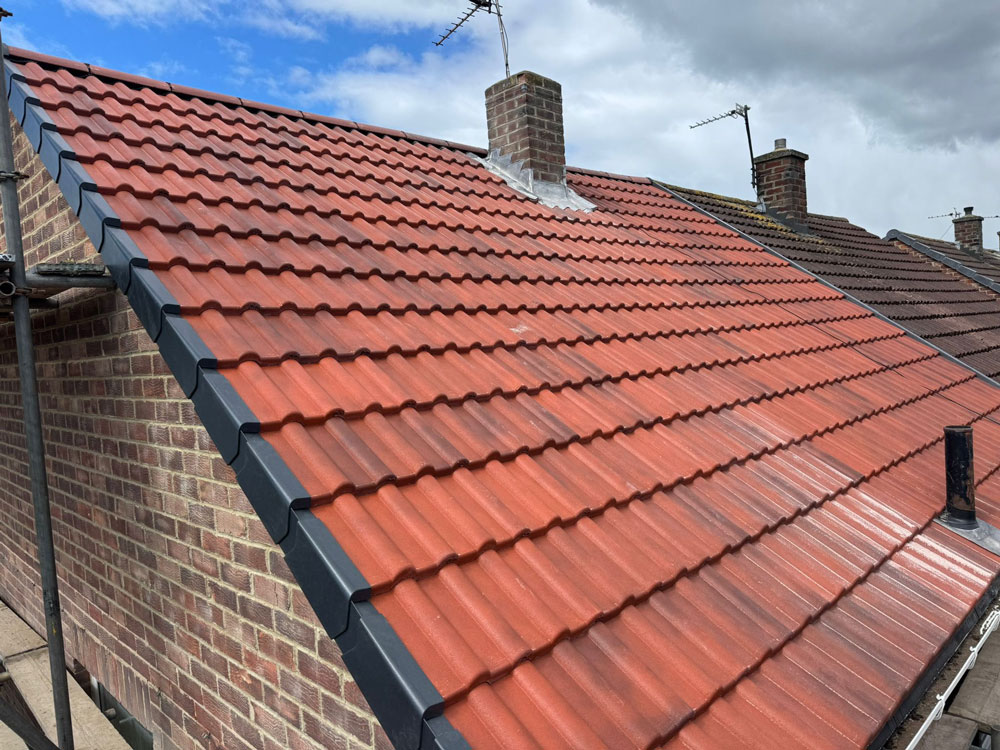 Recently completed pitched roof installation using red concrete roof tiles and new lead chimney flashing in Newcastle.