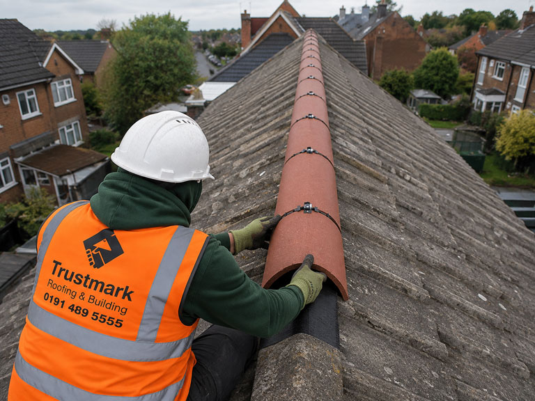 Roofer installing a mechanical dry ridge system on a tiled roof in Gateshead